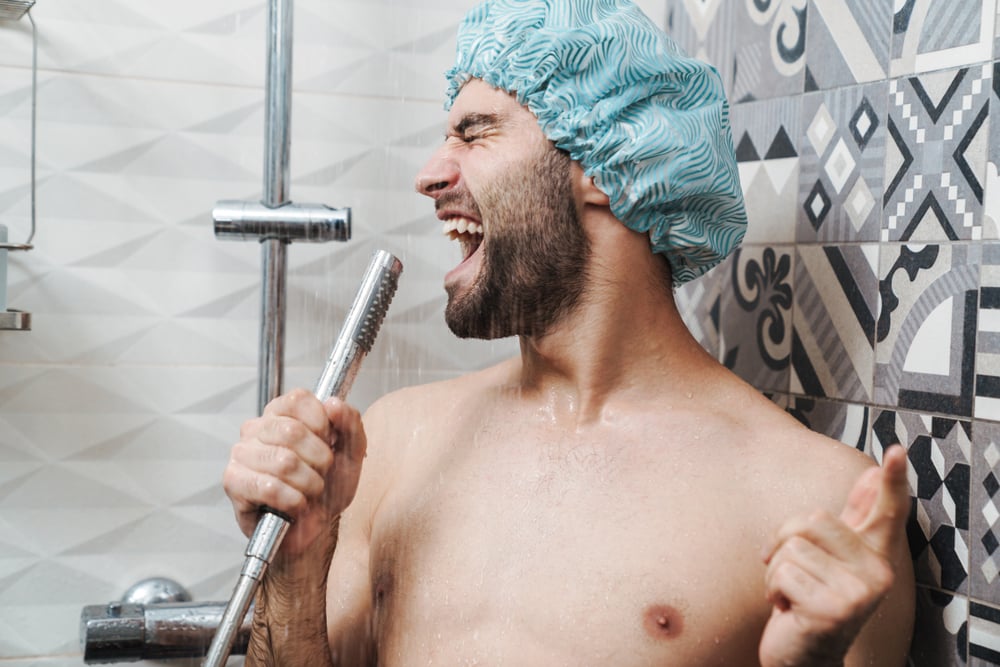 man singing in the shower with a beard a blue shower cap